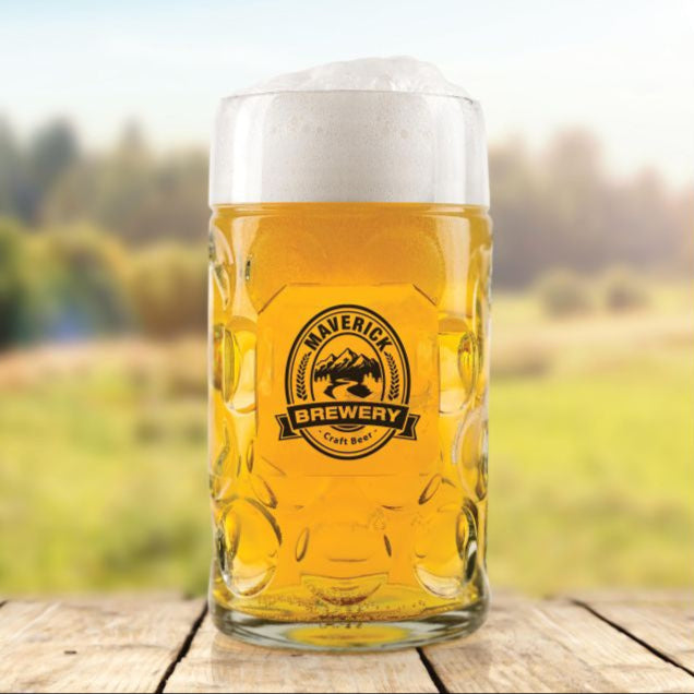 Beer glass with Maverick Brewery logo on a wooden surface with a blurred natural background