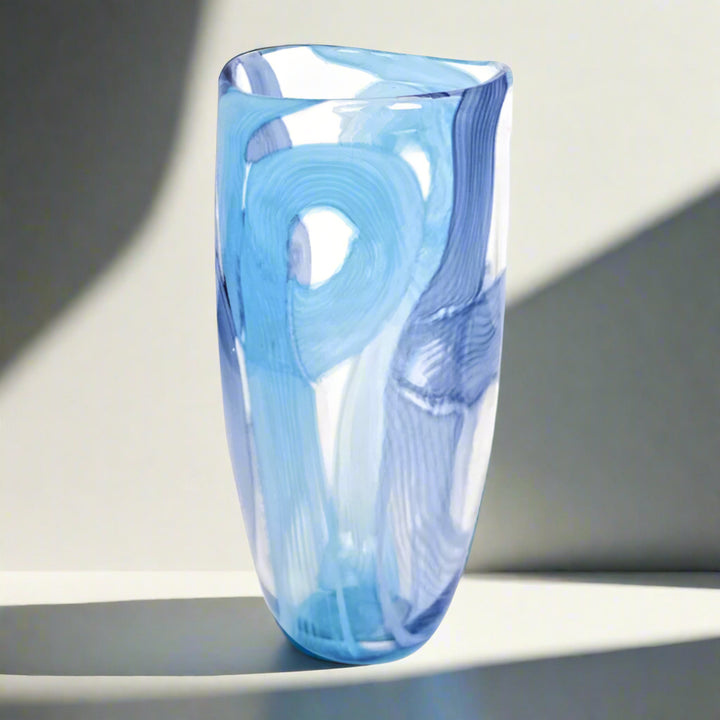 Blue glass vase with swirling pattern on a white background