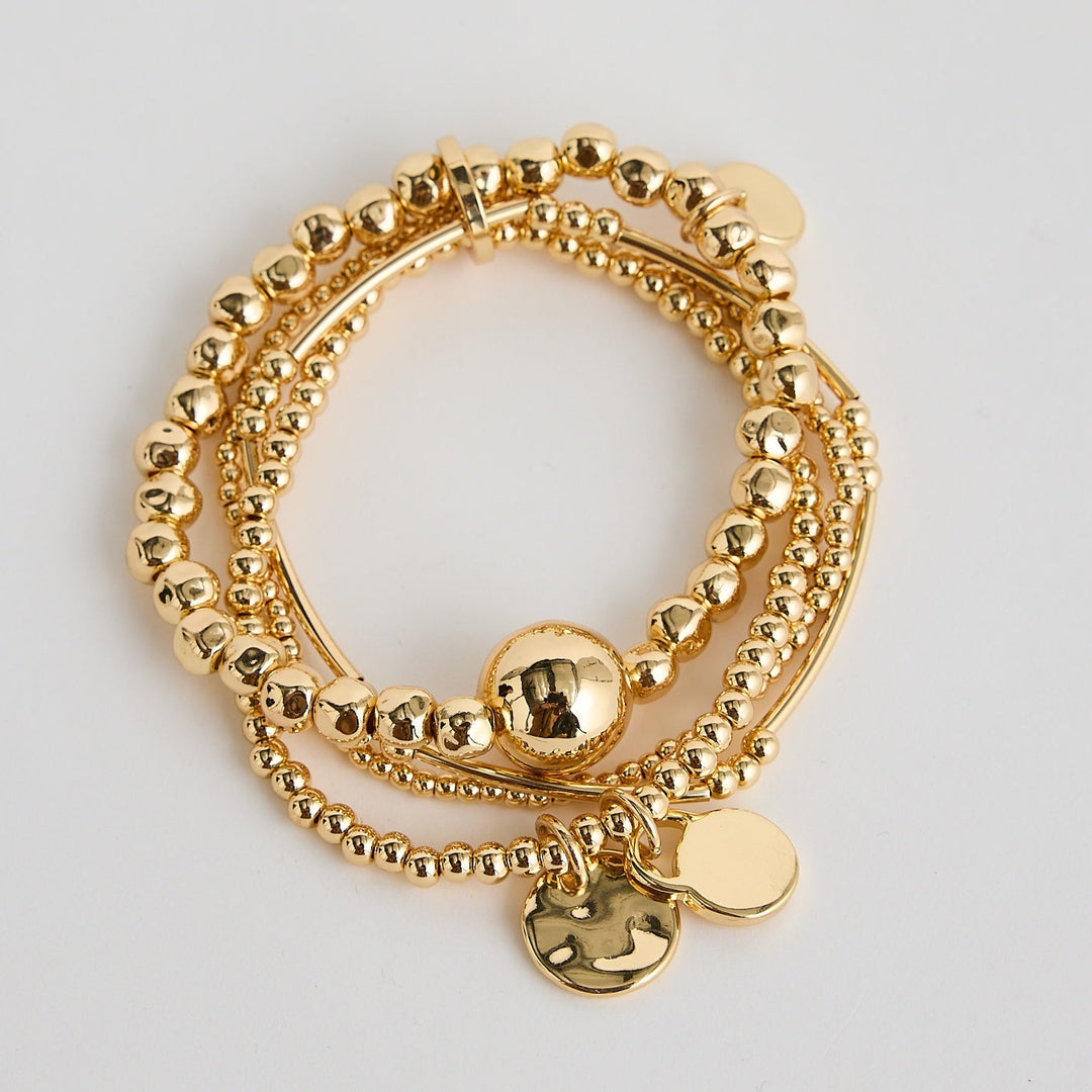Gold bracelets with various charms on a light gray background