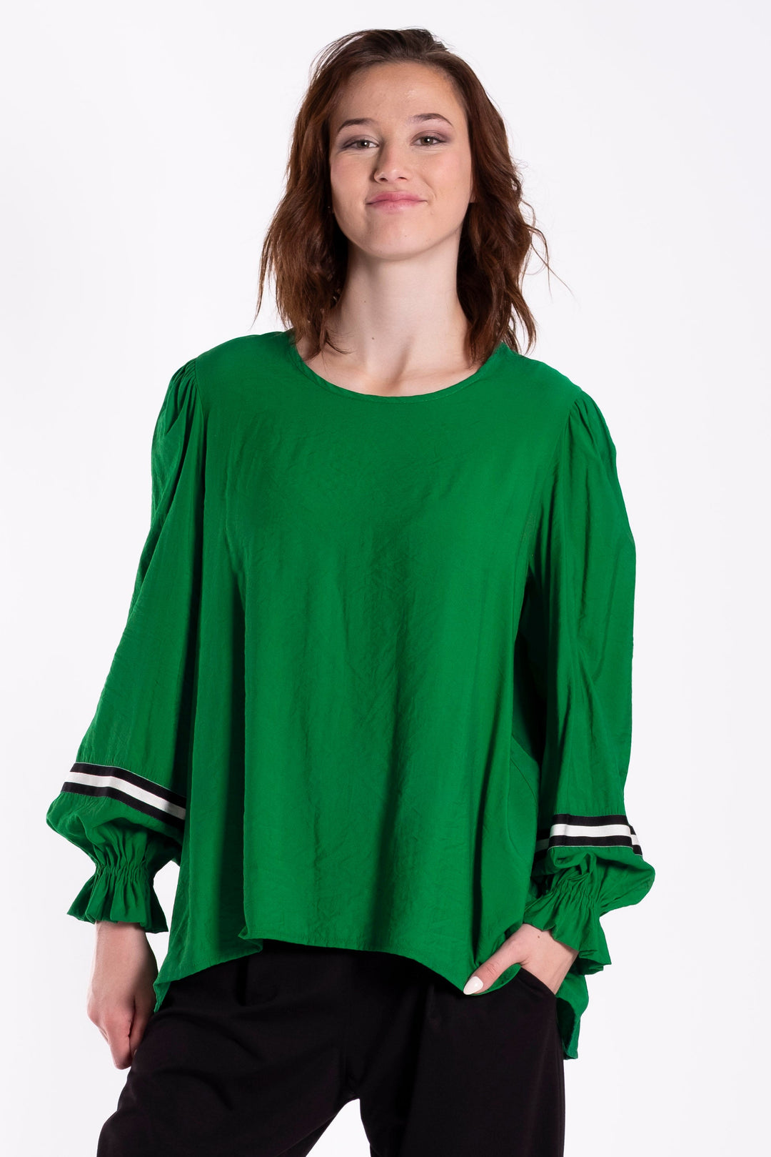 Woamnd wearing a very stylish green top designed by Deeanne Hobbs on a white background.