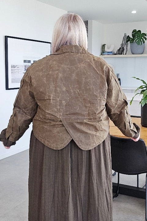 Person wearing a khaki coat and pants in a modern interior setting