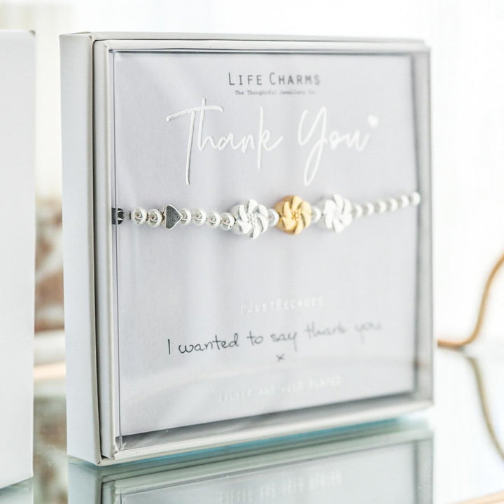 Bracelet with gold and silver charms on a 'Life Charms' card with 'Thank You' message.