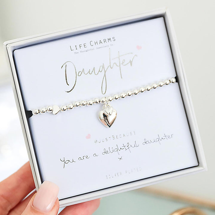 Heart-shaped necklace on a 'Daughters' card held by a hand