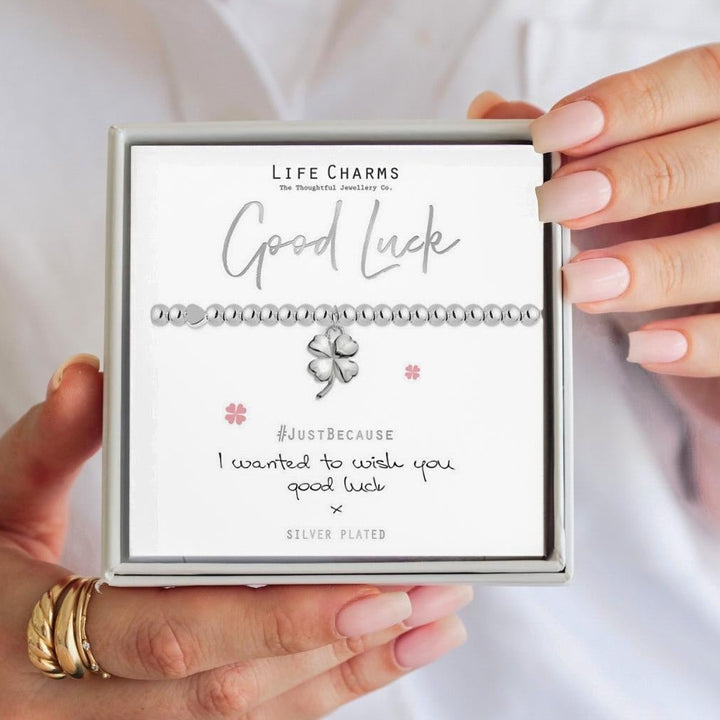 Person holding a box with 'Good Luck' message and Life Charms branding.