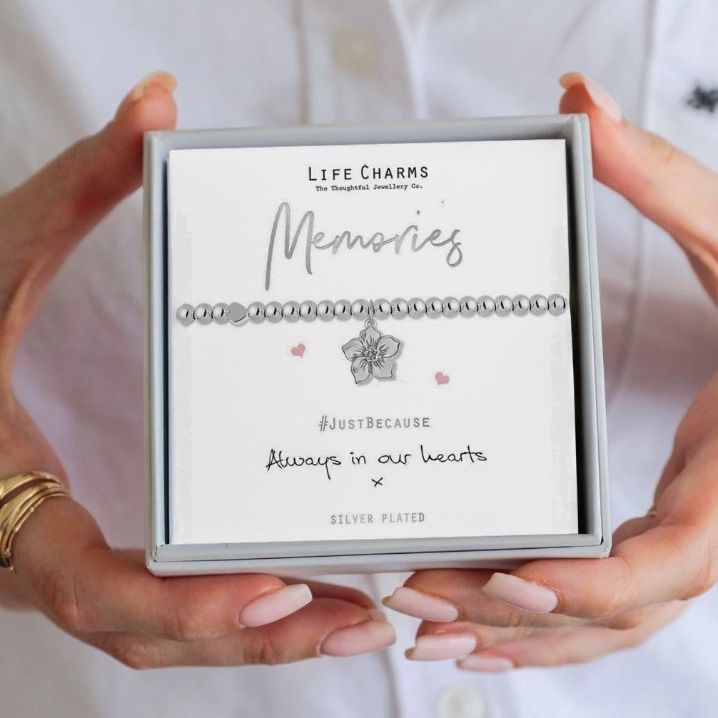 Person holding a box of Life Charms jewelry with 'Memories' text.