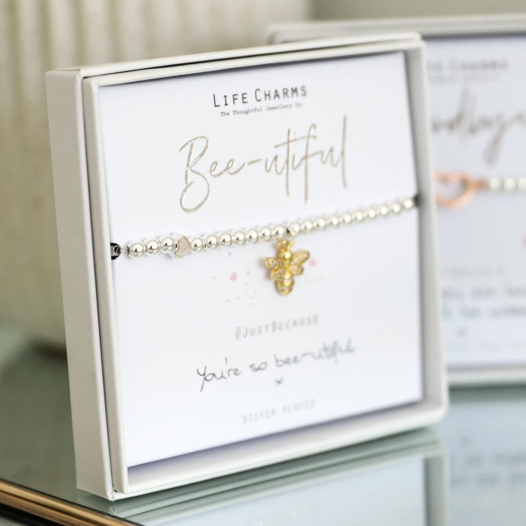 Gold bee bracelet on a card with 'Life Charms' branding on a reflective surface.