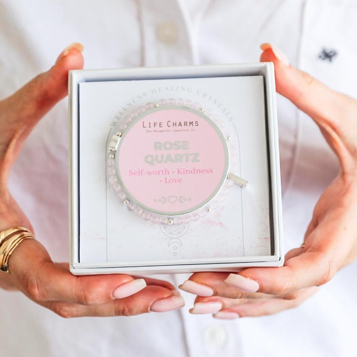 Person holding a Life Charms Rose Quartz pendant in a box