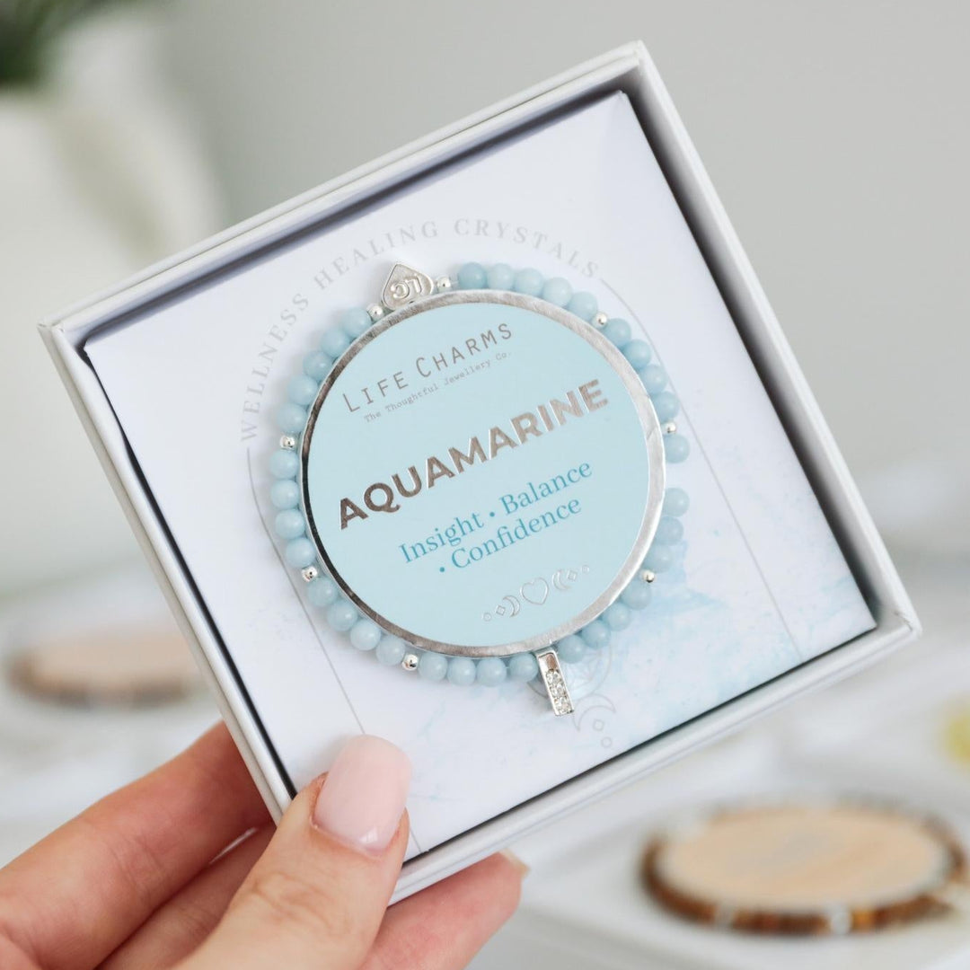Aquamarine bracelet in a box held by a hand with a blurred background