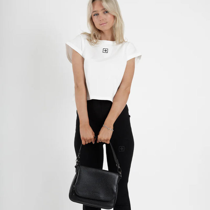 Woman holding a black handbag against a white background