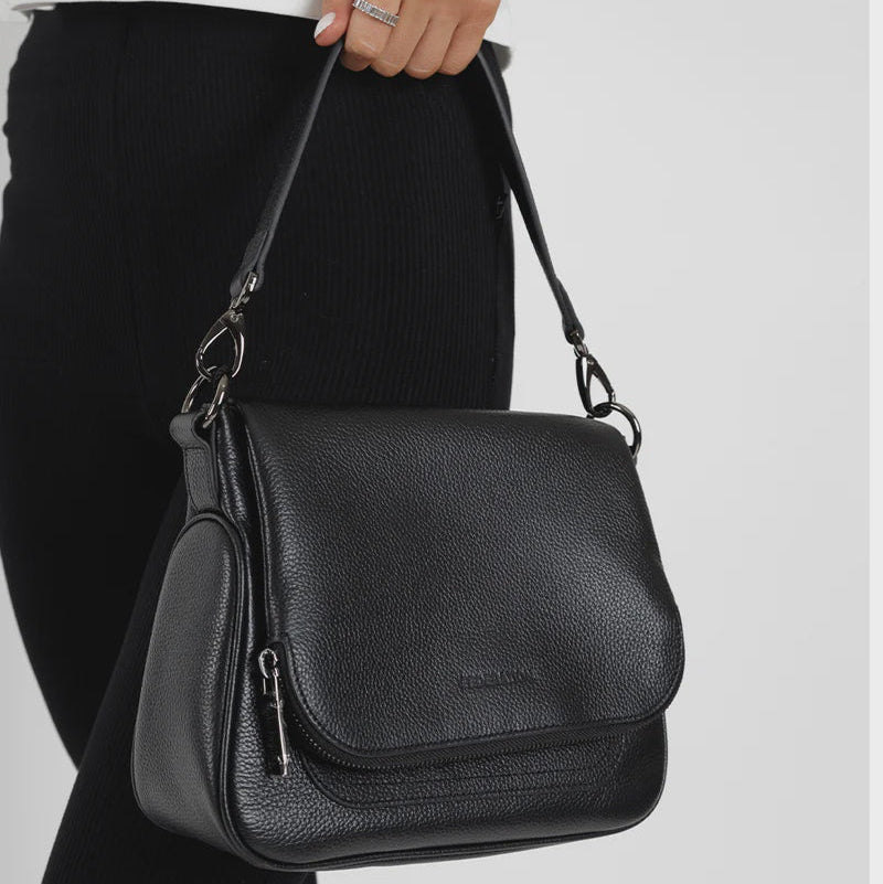 Person holding a black leather FEDERATION handbag against a plain background