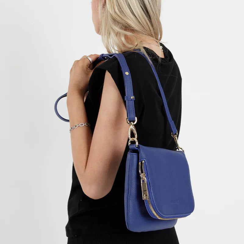 Woman holding a blue handbag against a white background