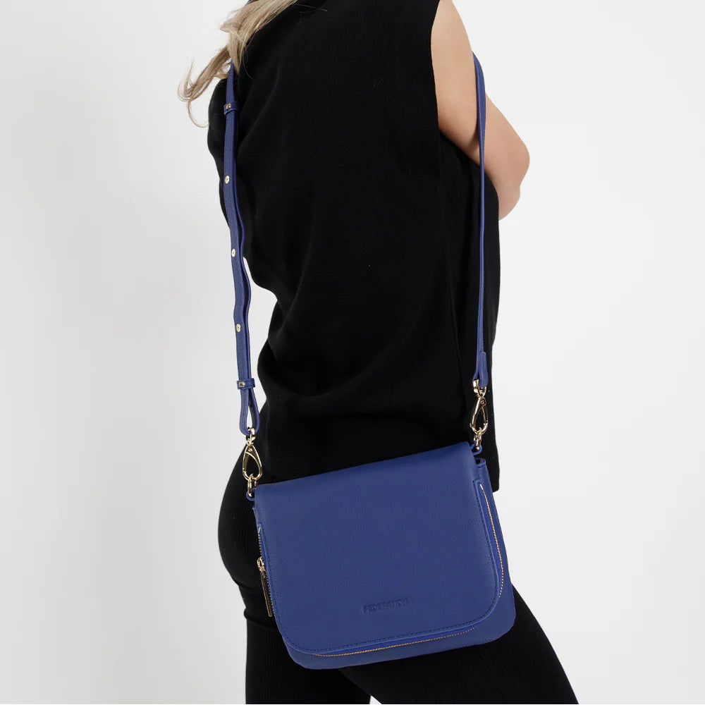 Woman wearing a blue crossbody bag on a white background