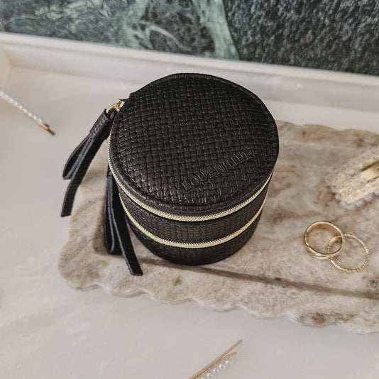 Black woven louenhide jewelry box with gold rings and hairpins on a marble surface