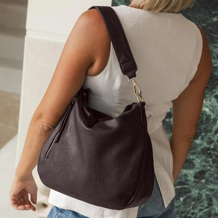 Woman carrying a black handbag in an indoor setting