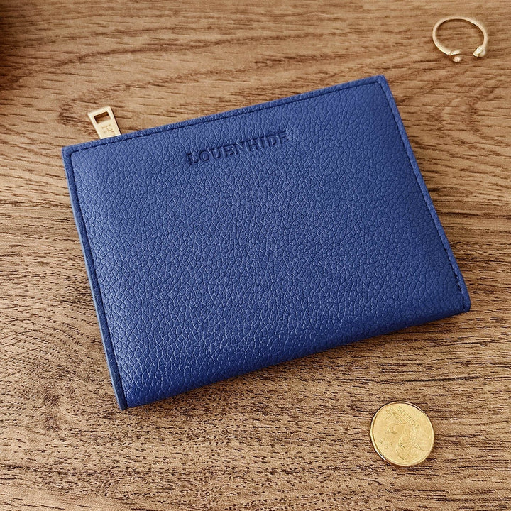 Blue louenhide vegan leather pouch on a wooden surface with coins around