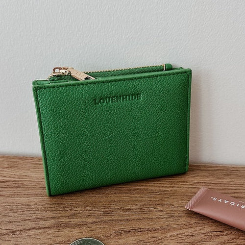 Green wallet on a wooden surface with coins and a pink item.