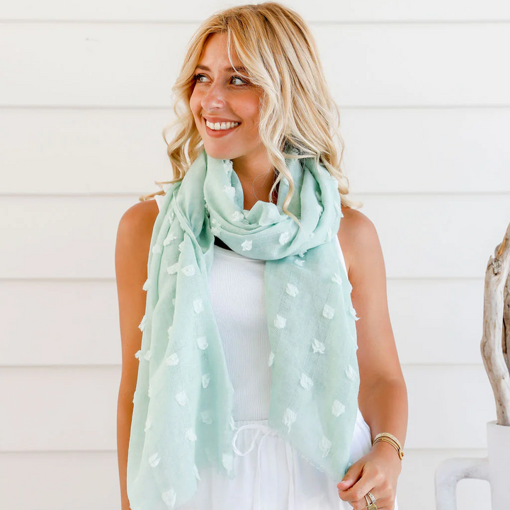 Woman wearing a light blue scarf with white polka dots in a casual setting.