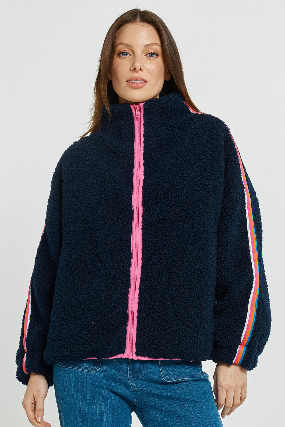 Woman wearing a dark blue fleece jacket with pink zipper and colorful side panels on a white background