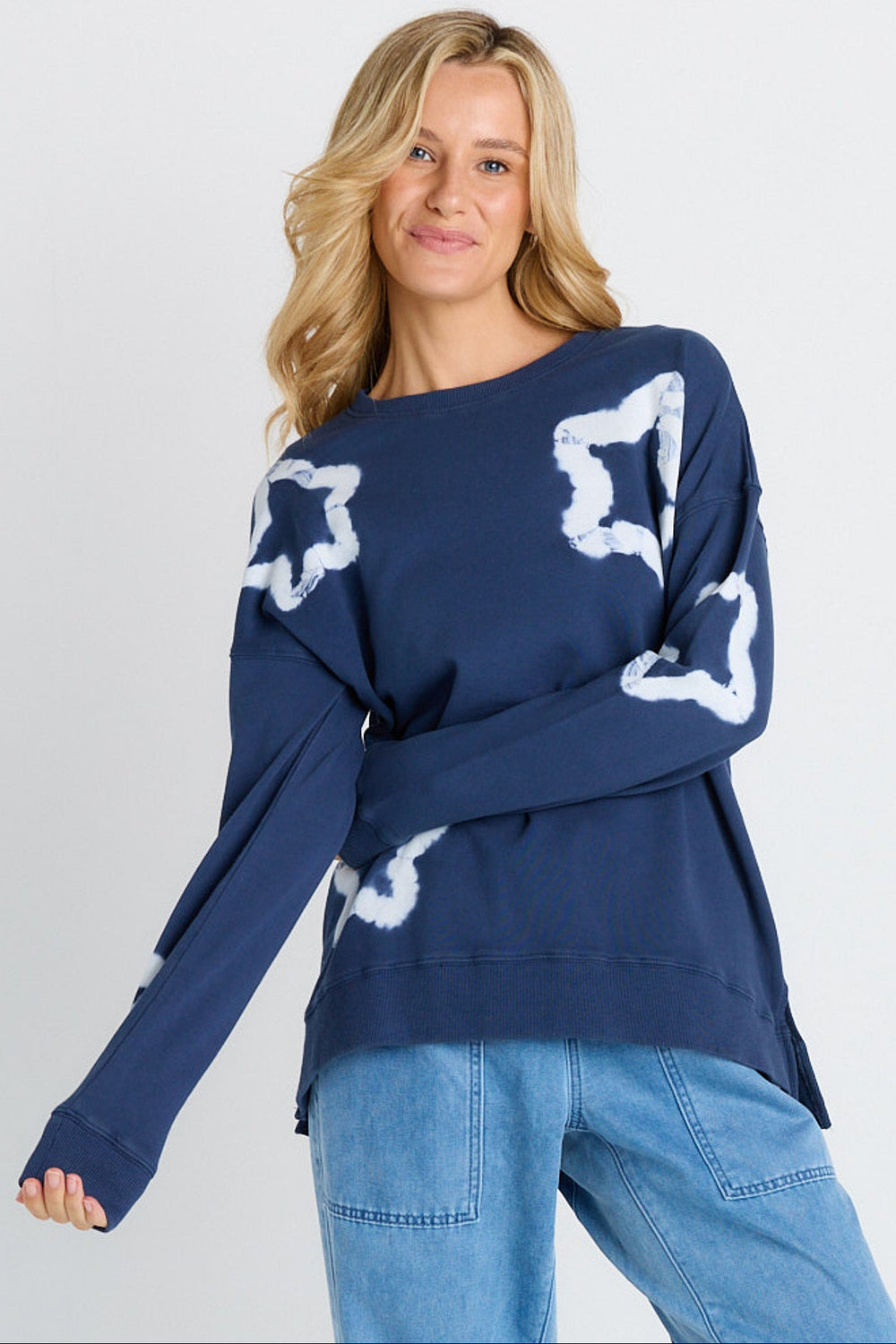Woman wearing a navy sweater with white star patterns on a plain background