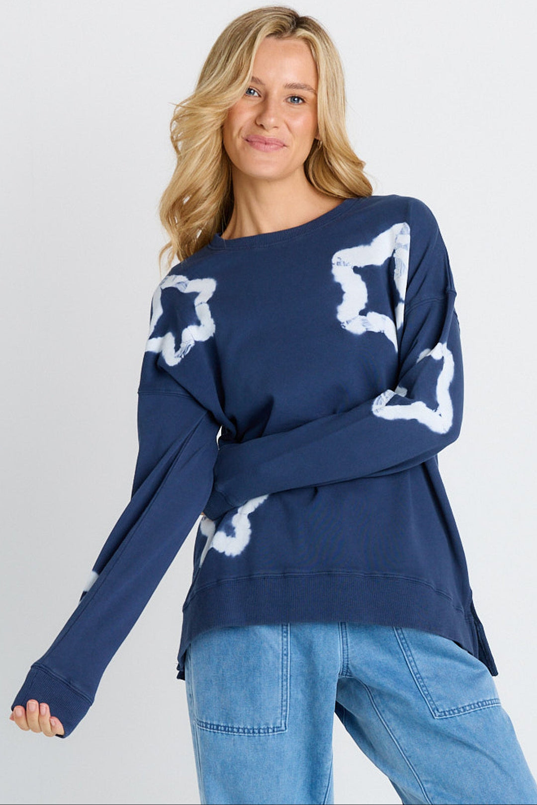 Woman wearing a navy sweater with white star patterns on a plain background
