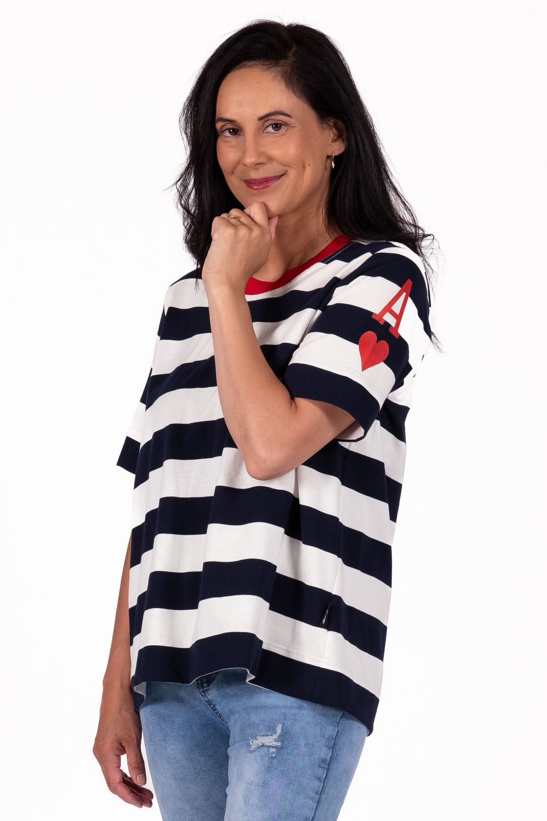 Woman wearing a black and white striped shirt, blue jeans, and red sneakers on a white background
