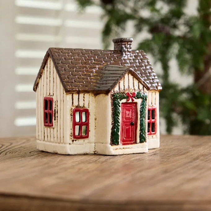 Decorative miniature house with a red door on a wooden surface