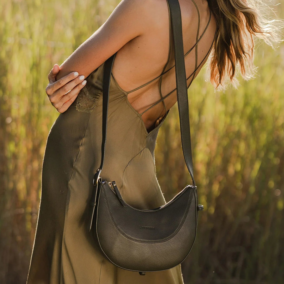Woman holding a black handbag in a field