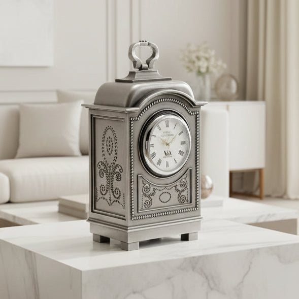 Decorative silver clock with intricate designs on a white background