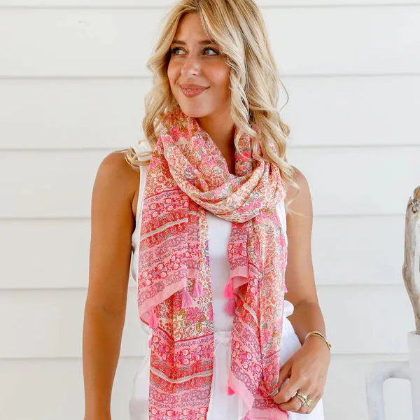 Woman wearing a pink scarf with white pants against a light background