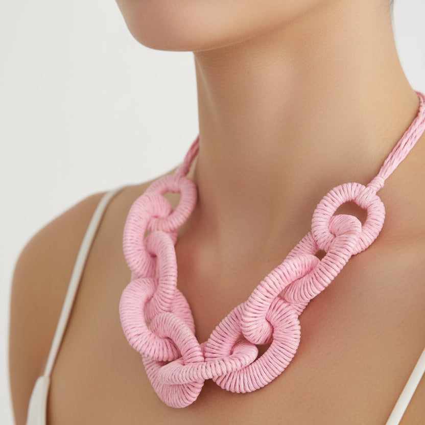 Pink knitted necklace on a mannequin against a white background