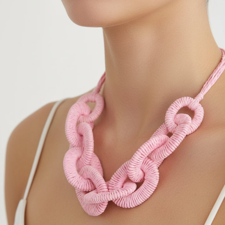 Pink knitted necklace on a mannequin against a white background