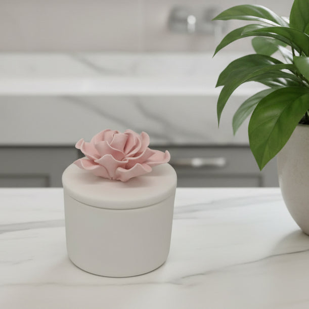 White decorative box with a pink flower on top against a light gray background