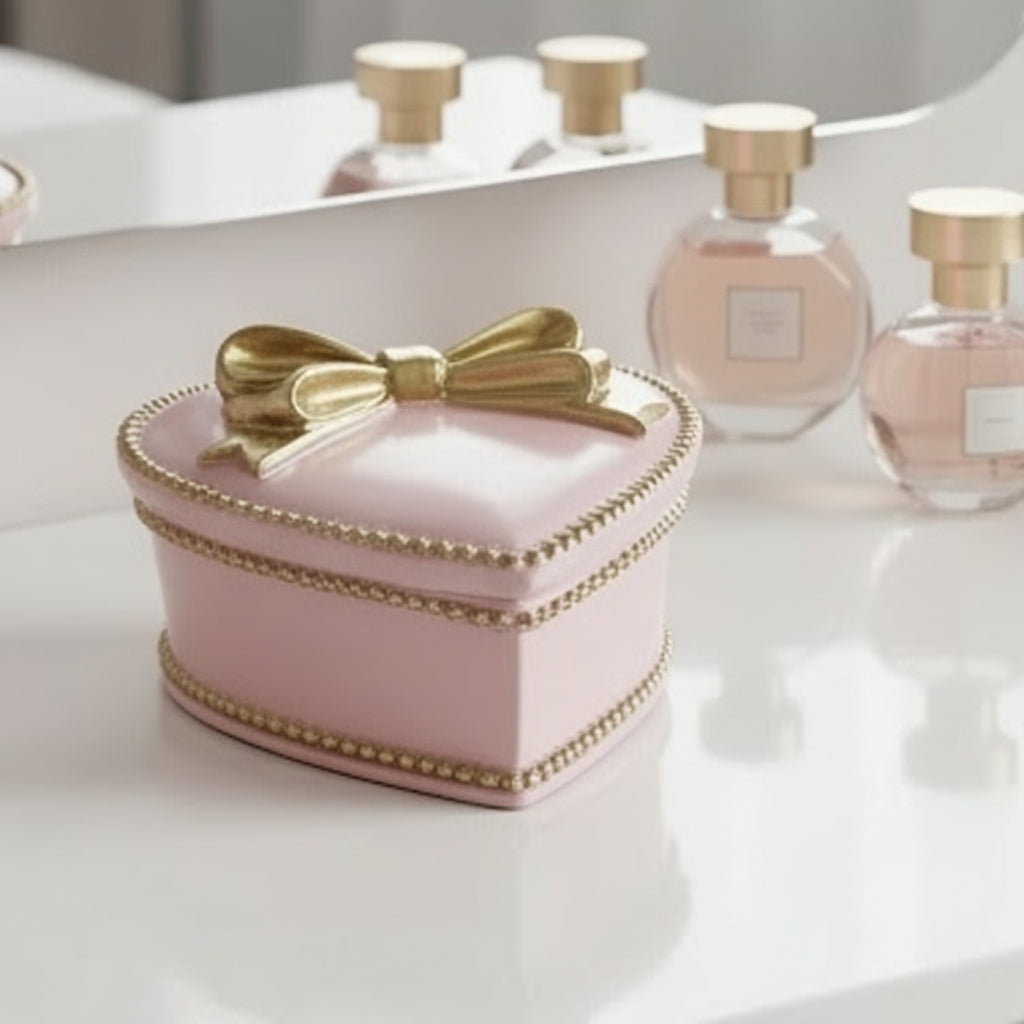 Pink heart-shaped box with a gold bow on a light gray background