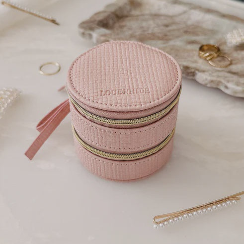 Pink louenhide jewelry box with gold accents on a marble surface