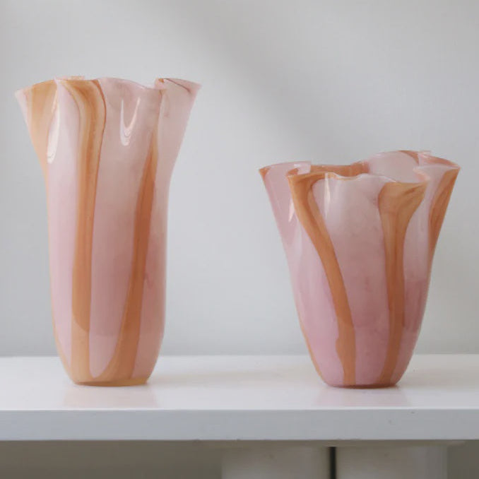 Two pink and orange striped vases on a white surface with a light gray background