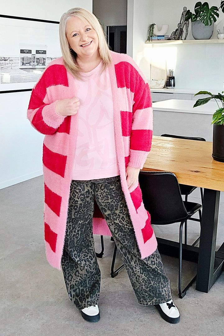 Woman in a pink and red striped cardigan standing in a modern living room.