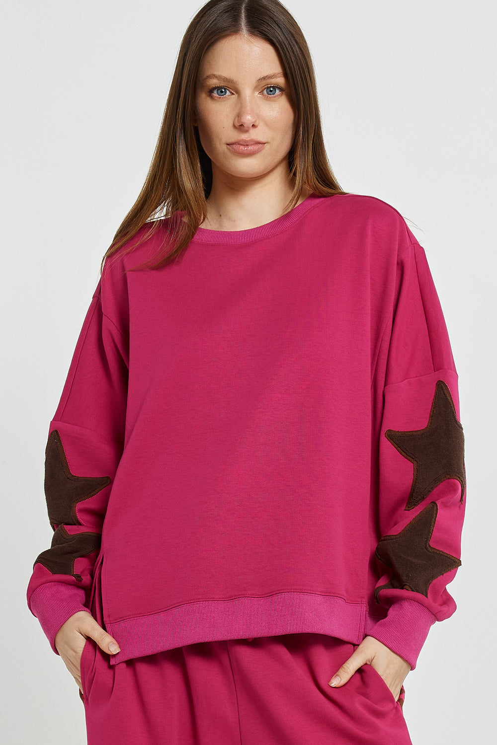Woman wearing a pink sweater with brown star designs on a white background