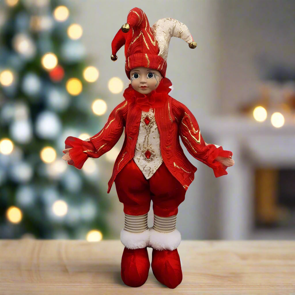 Doll dressed in a red jester outfit with a white hat on a white background