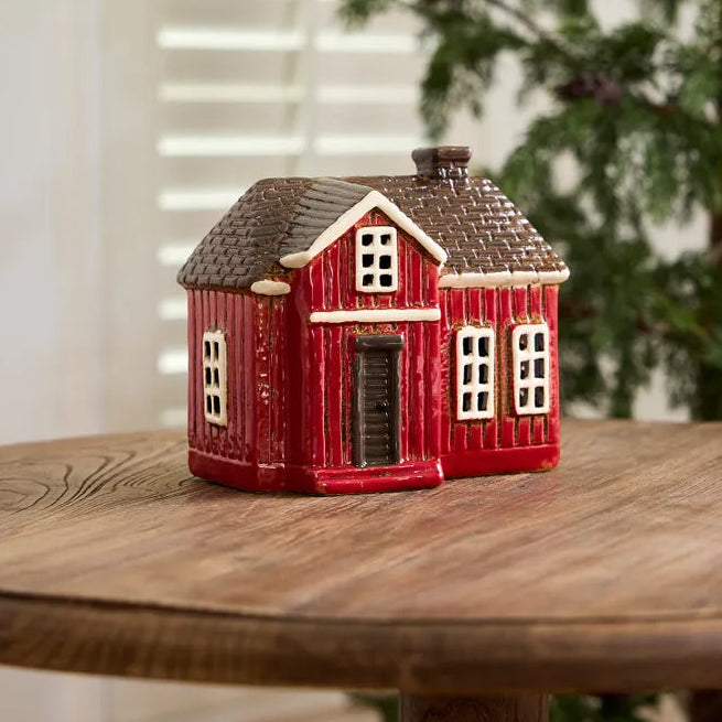Red house-shaped decorative item on a wooden table with a blurred background