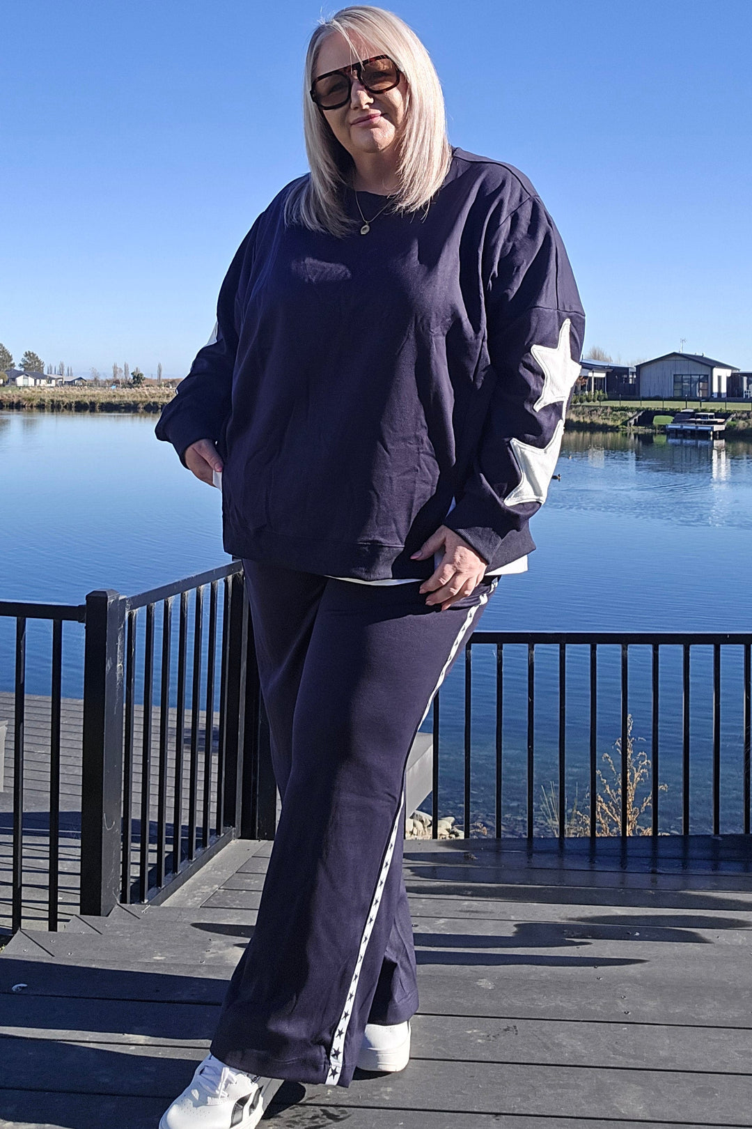 Person wearing a navy tracksuit with white stripes outdoors on a clear day