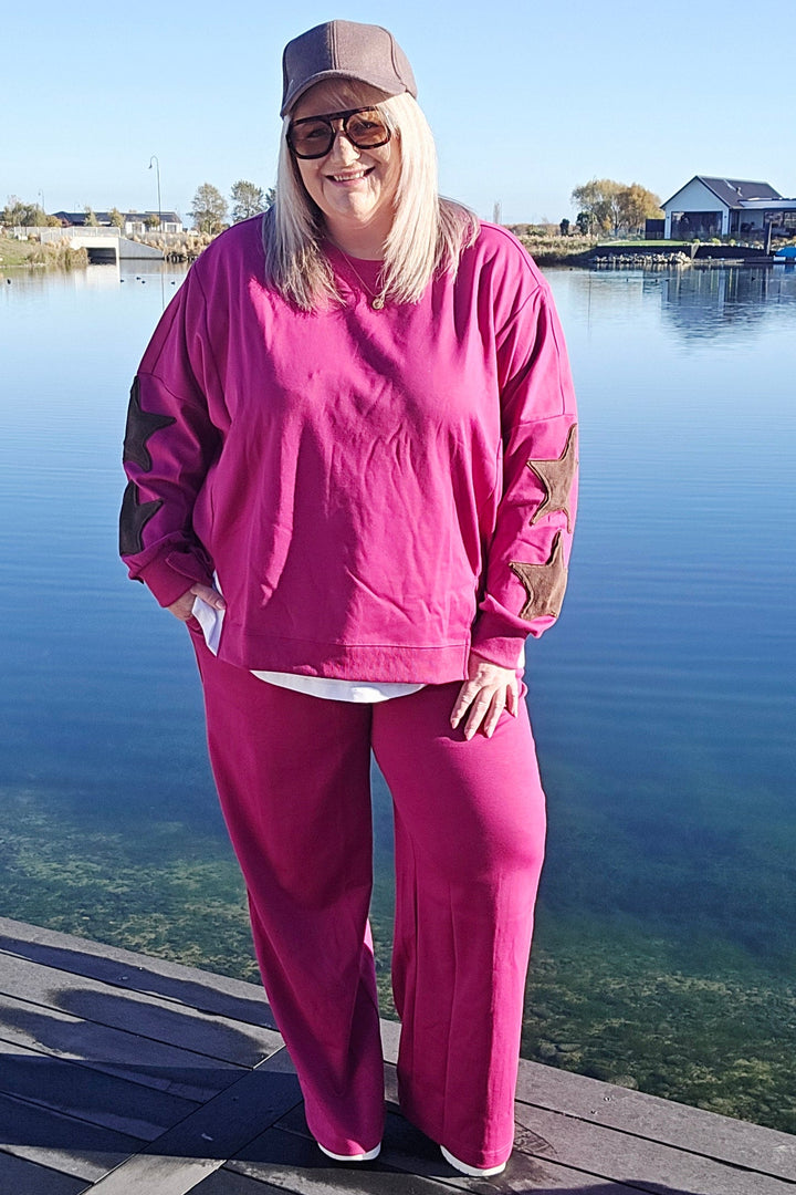 Person in pink outfit standing on a dock by a lake