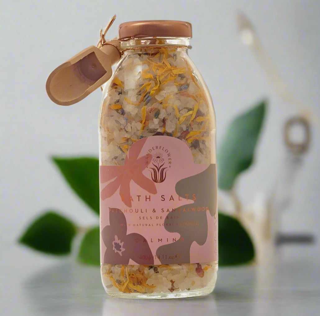 Glass jar of bath salts with a decorative label on a light gray background