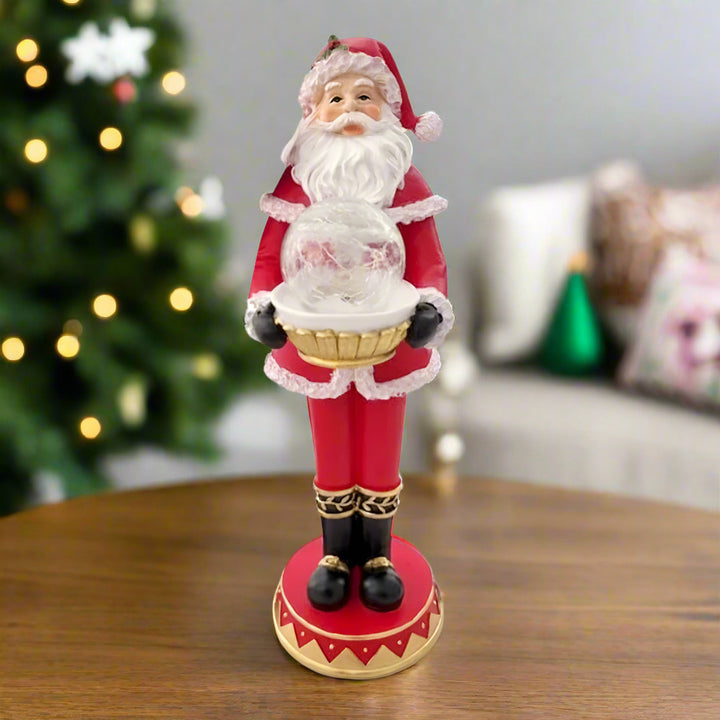 Santa Claus figurine holding a snow globe on a white background