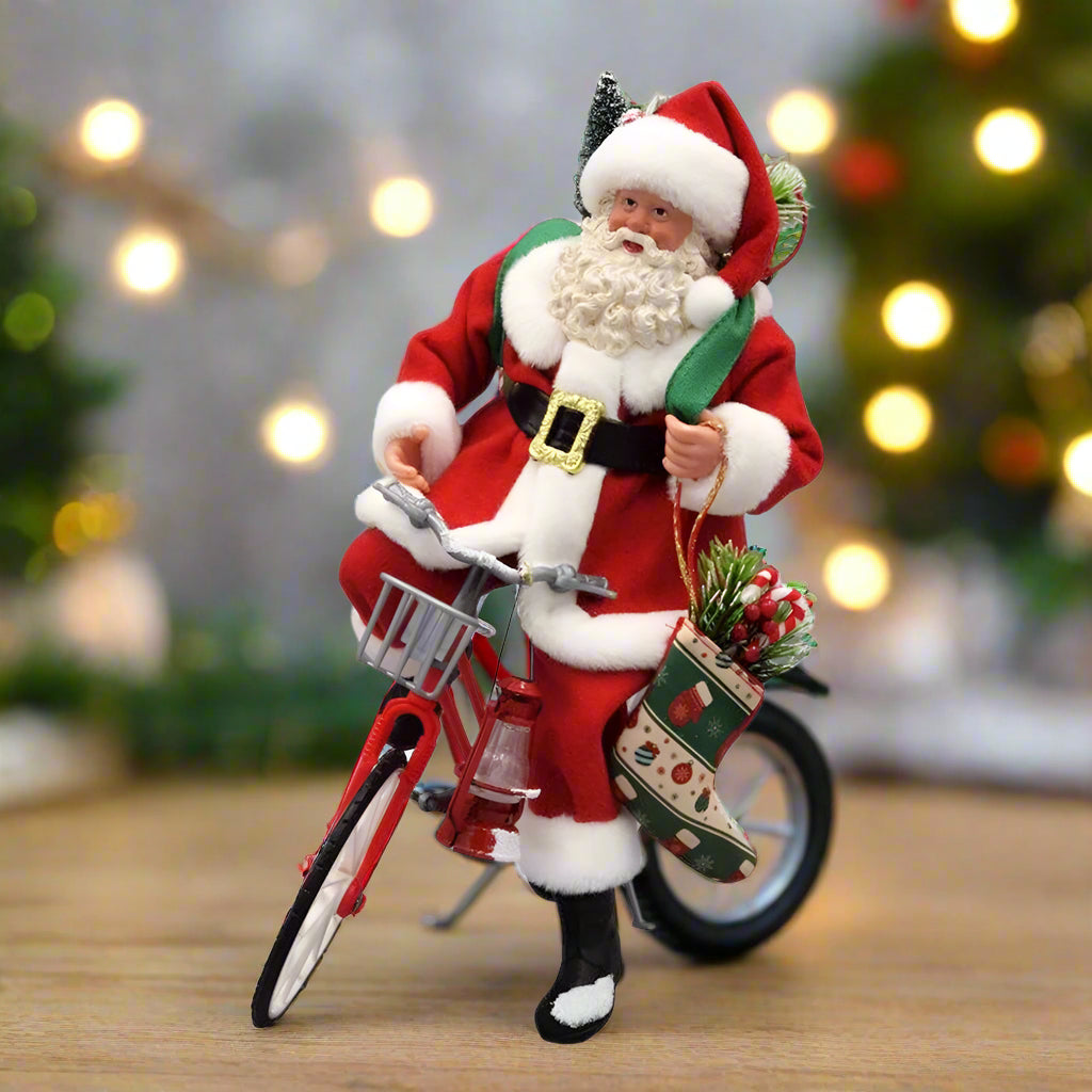 Decorative figure of Santa Claus riding a bicycle with a basket on a white background