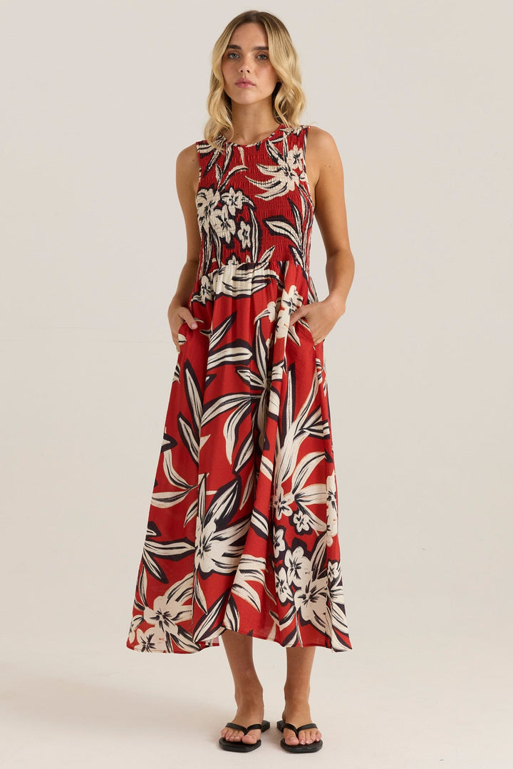 Woman wearing a red floral sass anella dress on a plain background