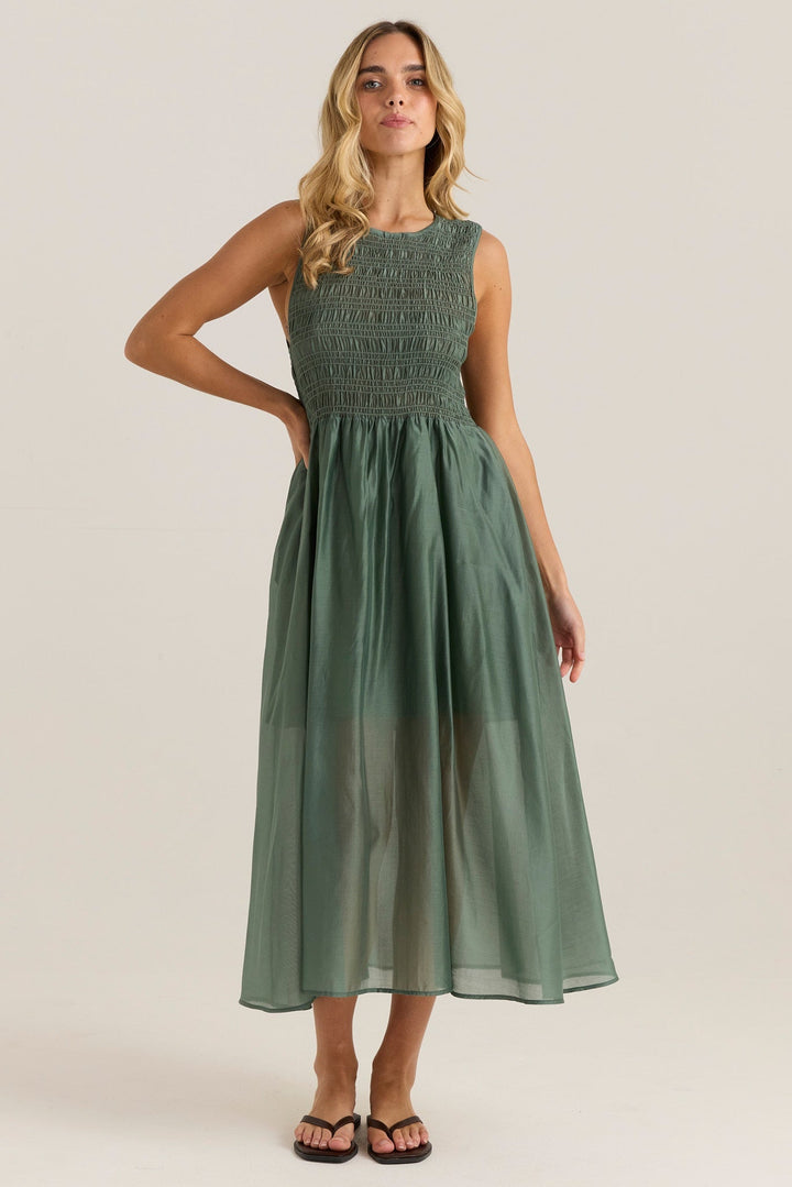 Woman wearing a green sass saga dress dress against a plain background