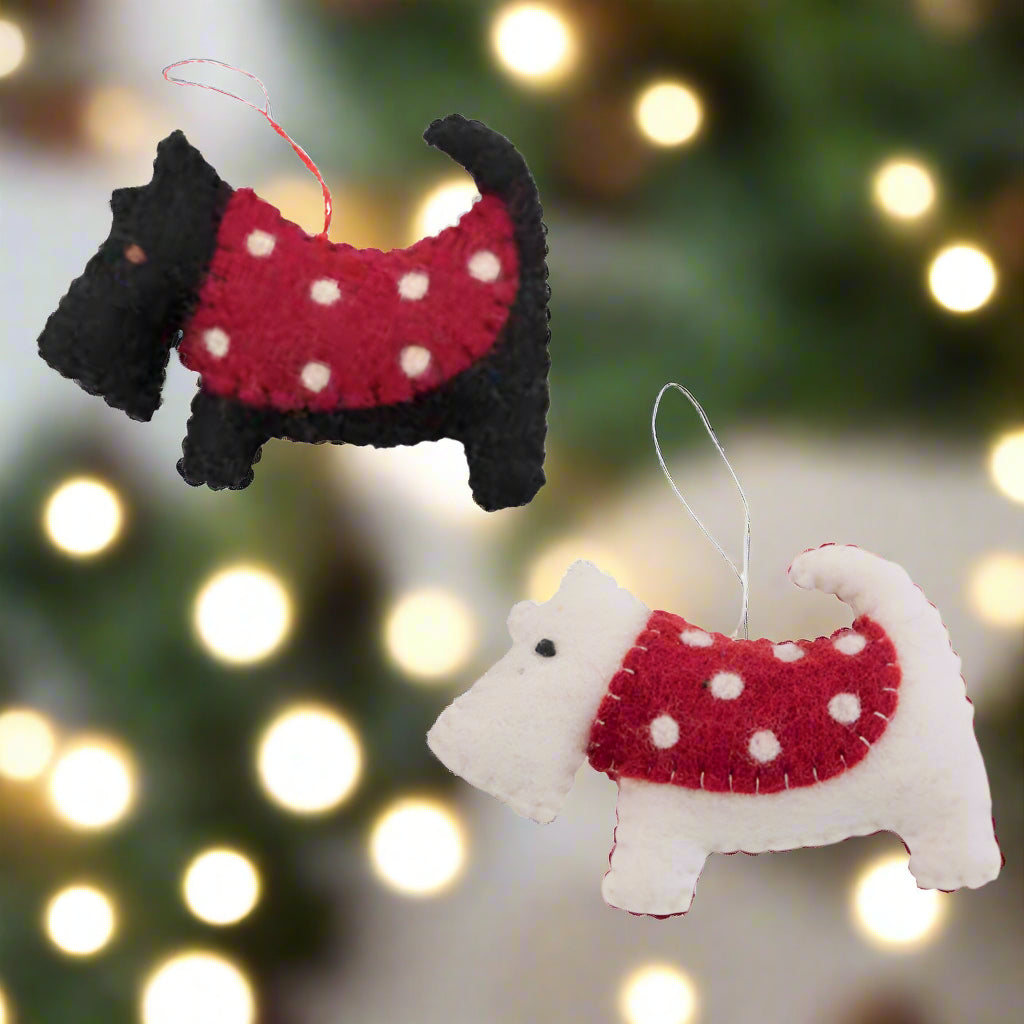 Two dog-shaped ornaments, one black and one white, wearing red sweaters with white polka dots on a white background.