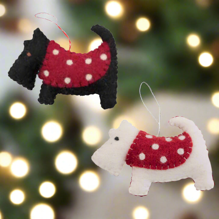 Two dog-shaped ornaments, one black and one white, wearing red sweaters with white polka dots on a white background.
