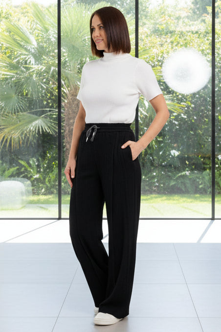 Woman wearing a white top and black wide-leg pants on a white background