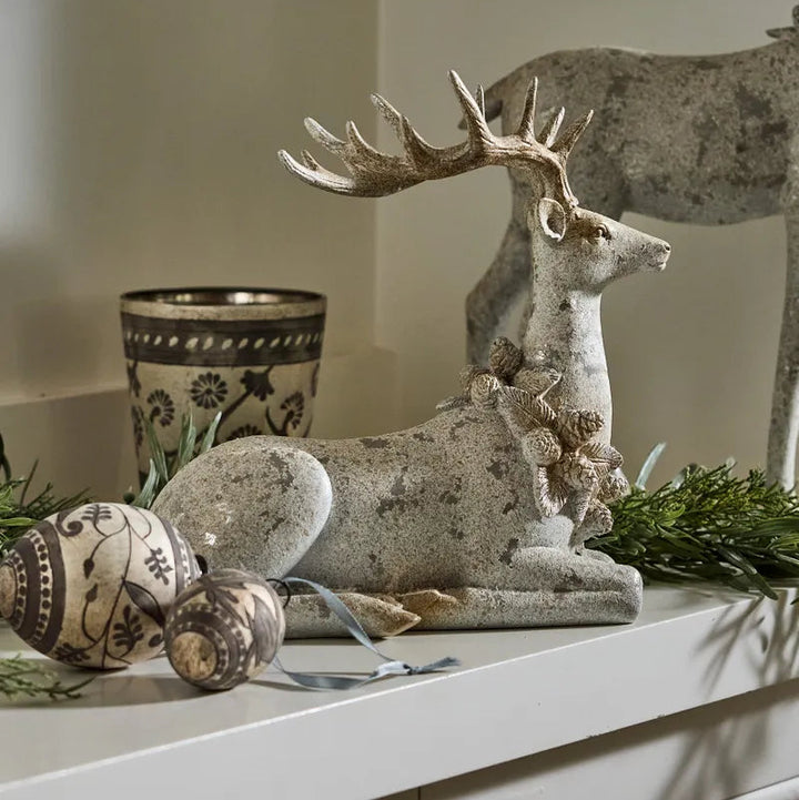 Decorative stone deer figure on a shelf with a cup and eggs in the background.